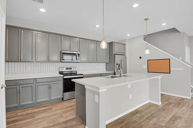 a large kitchen with stainless steel appliances a large counter top and wooden floors