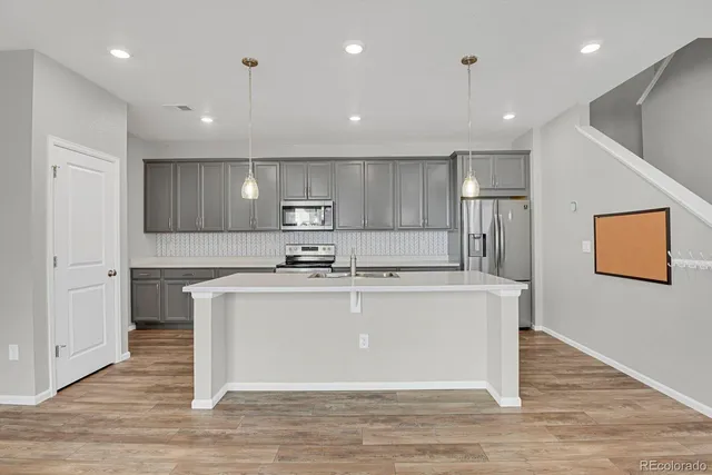 a kitchen with a sink stainless steel appliances and wooden floor