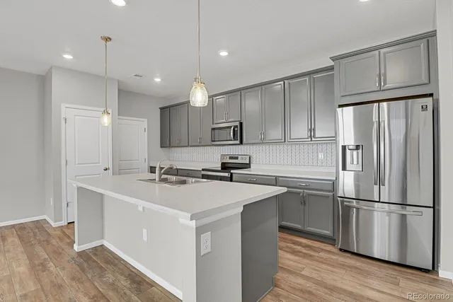 a kitchen with a sink chandelier and wooden floor