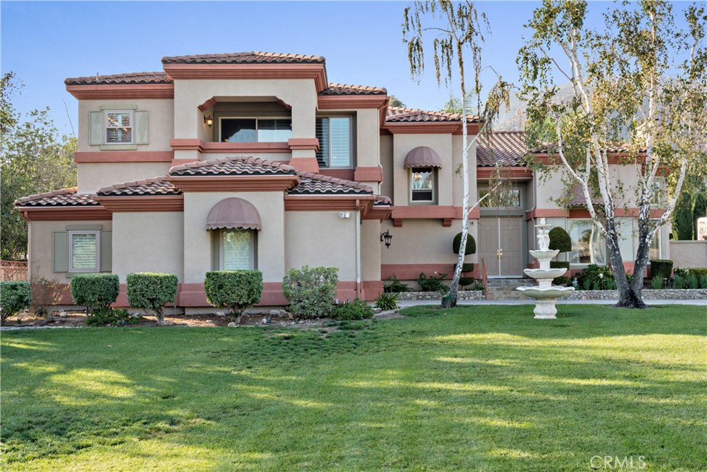 a front view of a house with a garden and trees