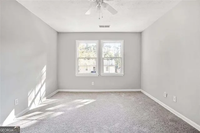 an empty room with a window and a ceiling fan