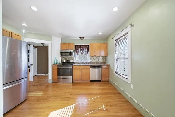 a large kitchen with stainless steel appliances kitchen island granite countertop a refrigerator and a stove top oven