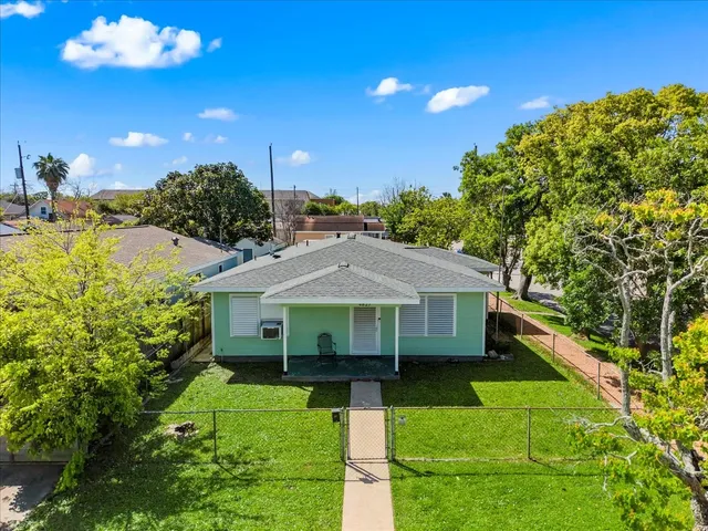 a view of a house with a yard plants and large tree