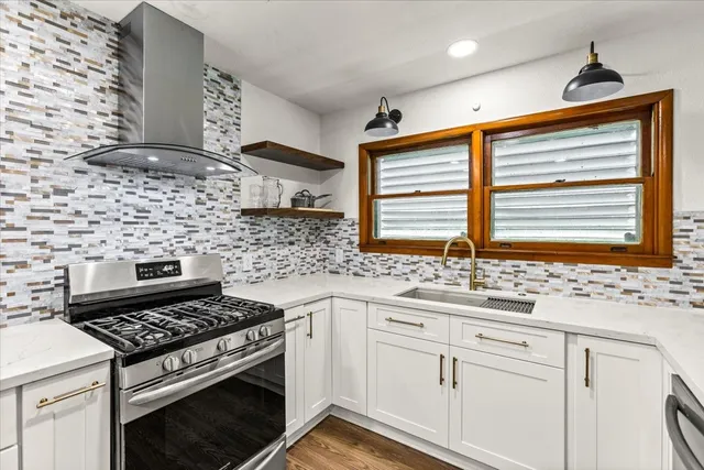 a kitchen with stainless steel appliances a stove a sink cabinet and a window