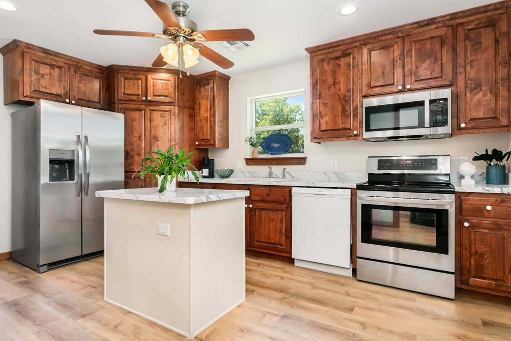 901 Bell Street Fredericksburg, TX 78624 - Photo 3 of 25 a kitchen with stainless steel appliances granite countertop a stove a microwave and a refrigerator