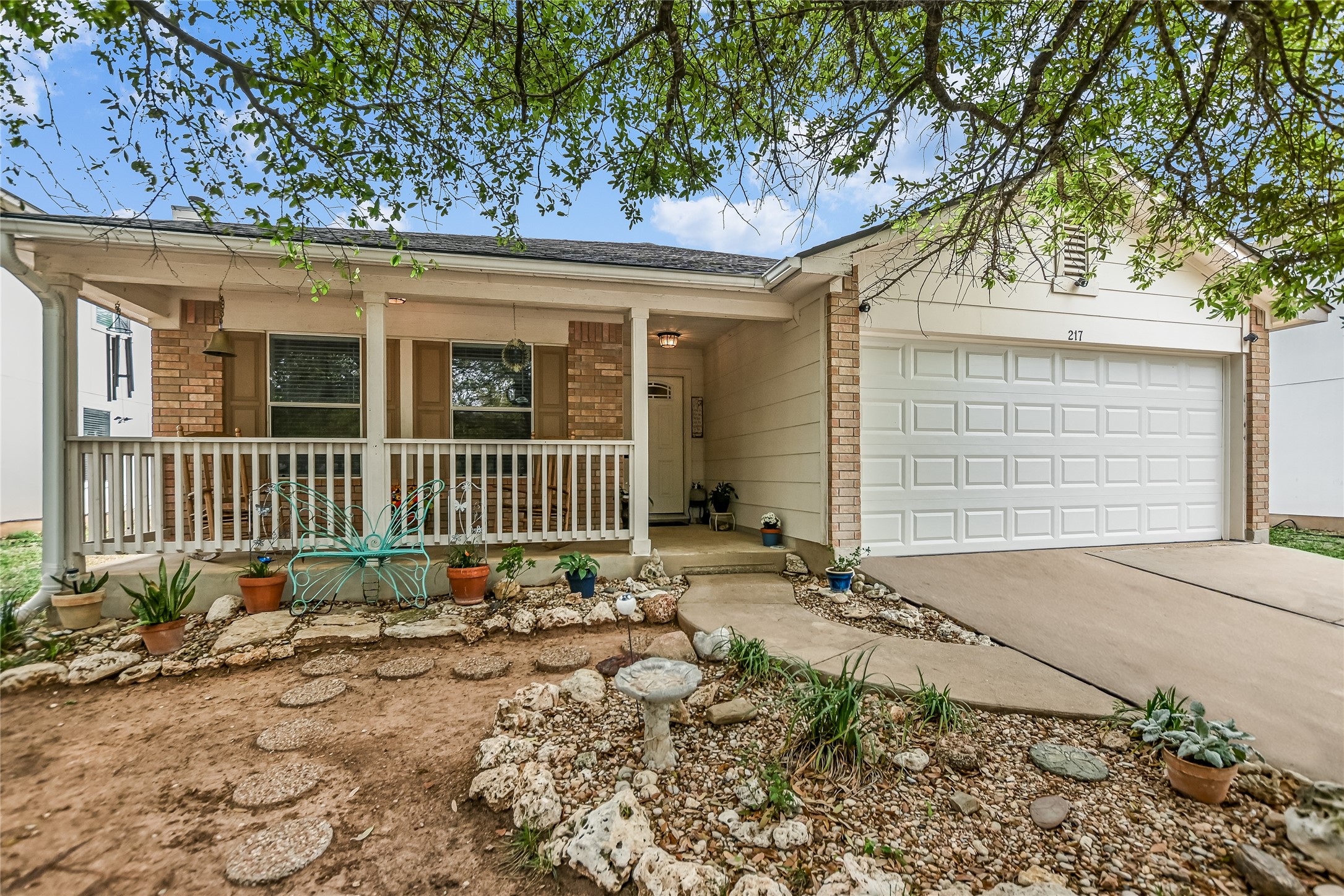Single story home featuring brick siding, a porch, driveway, and an attached garage