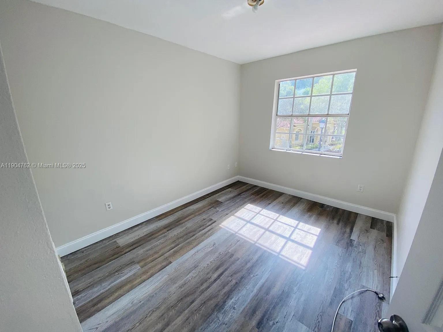 4947 Southwest 135th Way Miramar, FL 33027 - Photo 13 of 17 an empty room with wooden floor and windows