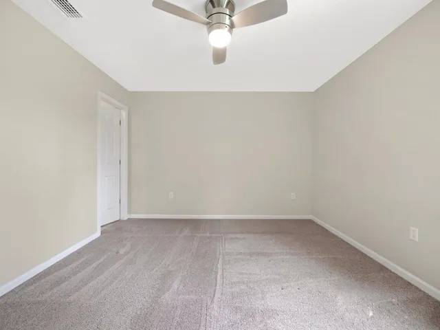 an empty room with a ceiling fan and window