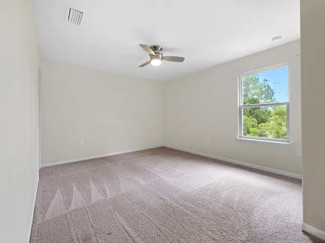 an empty room with a window and ceiling fan