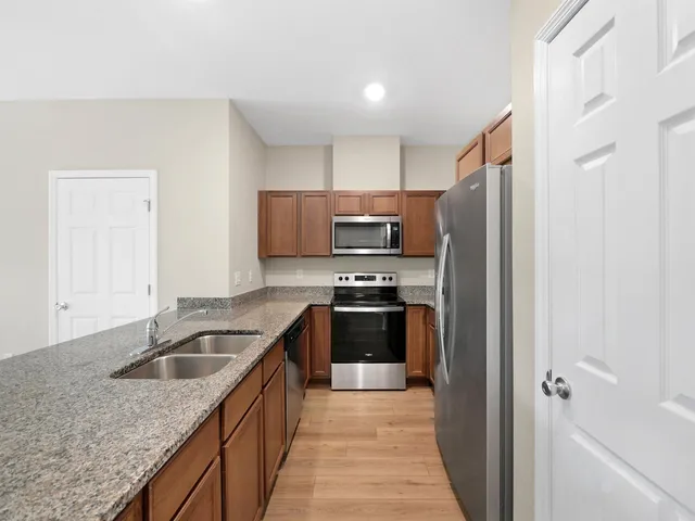 a kitchen with a granite countertop sink stove and refrigerator