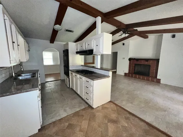a kitchen with granite countertop a sink and white cabinets
