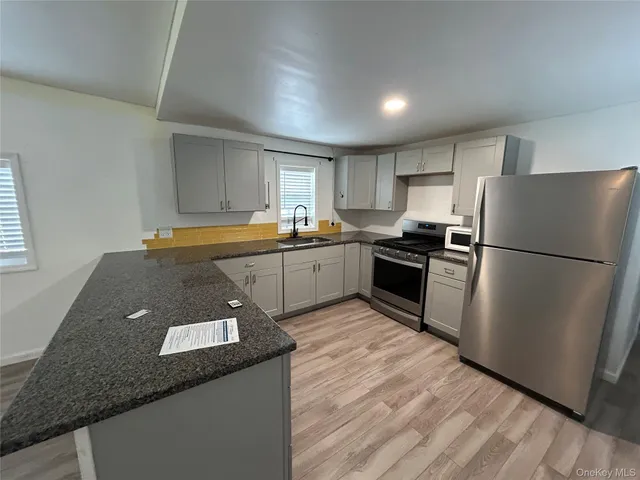 a kitchen with granite countertop stainless steel appliances a refrigerator sink and microwave