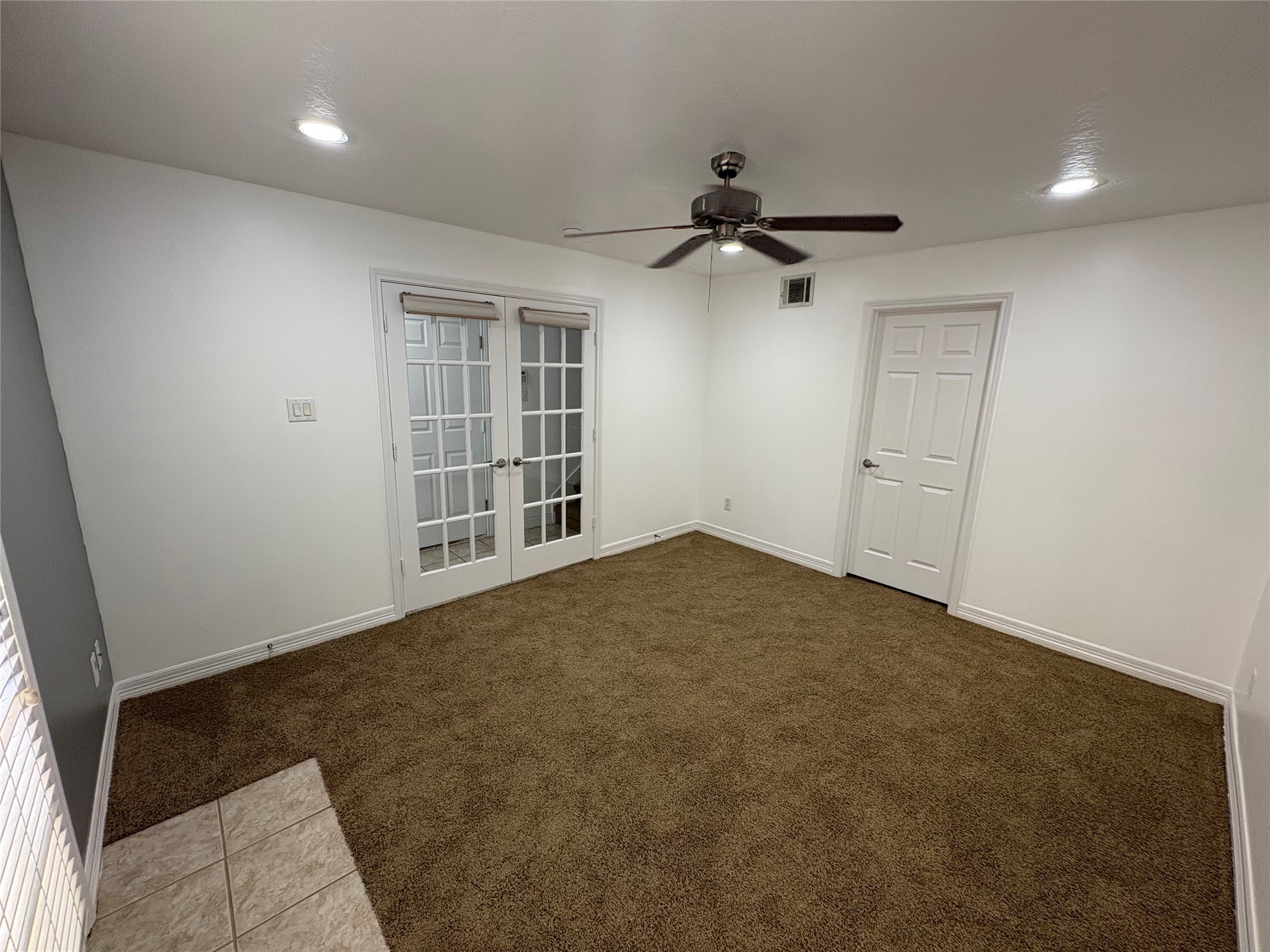 3710 Sherwood Lane, Unit 102 Houston, TX 77092 - Photo 20 of 27 Downstairs Bedroom features a cozy carpeted area with recessed lighting, a ceiling fan, and French doors. It has access to an outdoor space through double doors with blinds, offering natural light and versatile use. Perfect for guests or home-office space