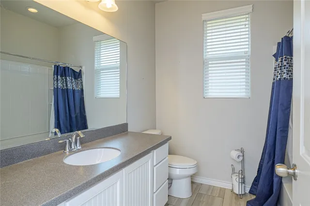 a bathroom with a granite countertop toilet sink and mirror