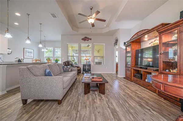 a living room with stainless steel appliances furniture wooden floor and a view of kitchen
