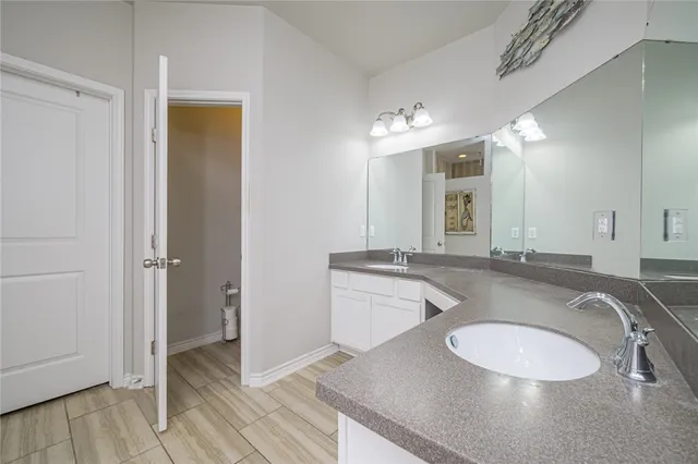 a bathroom with a granite countertop double vanity sink and a mirror