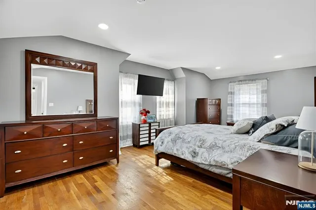 a bedroom with a bed and a flat tv screen on dresser