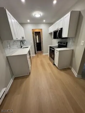 a large kitchen with stainless steel appliances a stove a sink a microwave and cabinets