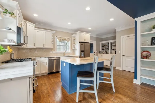 a kitchen with stainless steel appliances kitchen island granite countertop a table chairs sink and cabinets