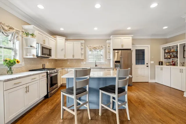 a kitchen with kitchen island granite countertop wooden floors and white cabinets
