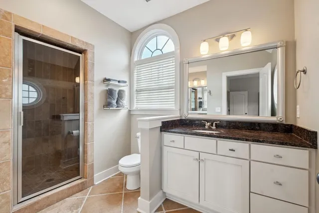 a bathroom with a granite countertop sink a toilet a mirror and shower