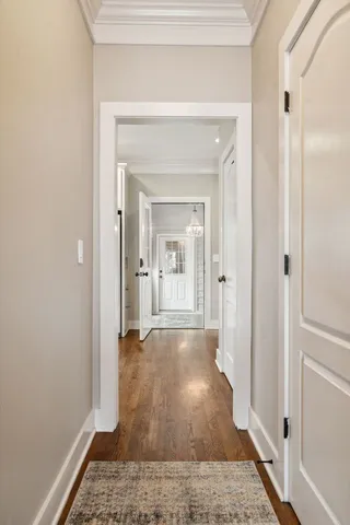 a view of a hallway with wooden floor and a bathroom