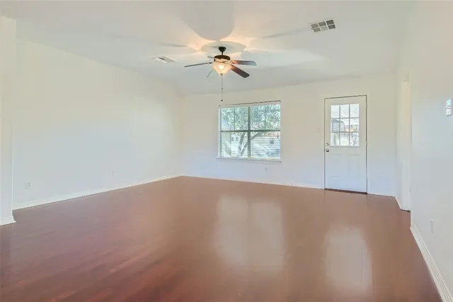 an empty room with windows and fan