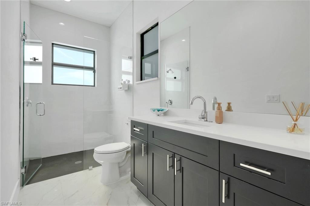 491 9th Street Southwest Naples, FL 34117 - Photo 22 of 49 a bathroom with a sink a toilet a mirror and a window