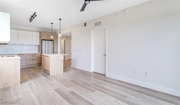 a view of a kitchen with a sink and dishwasher a refrigerator with wooden floor