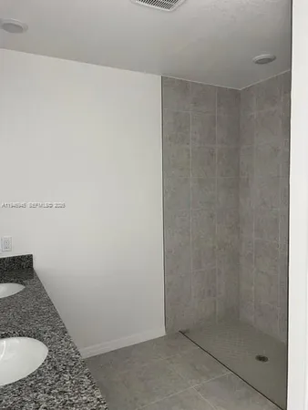 a bathroom with a granite countertop sink and shower