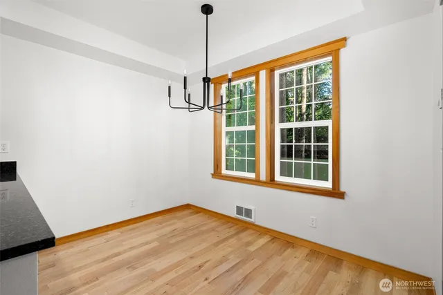 a view of an empty room with a window and hardwood floor