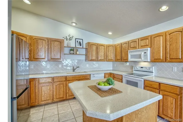 a kitchen with kitchen island granite countertop a sink a stove counter top space and cabinets