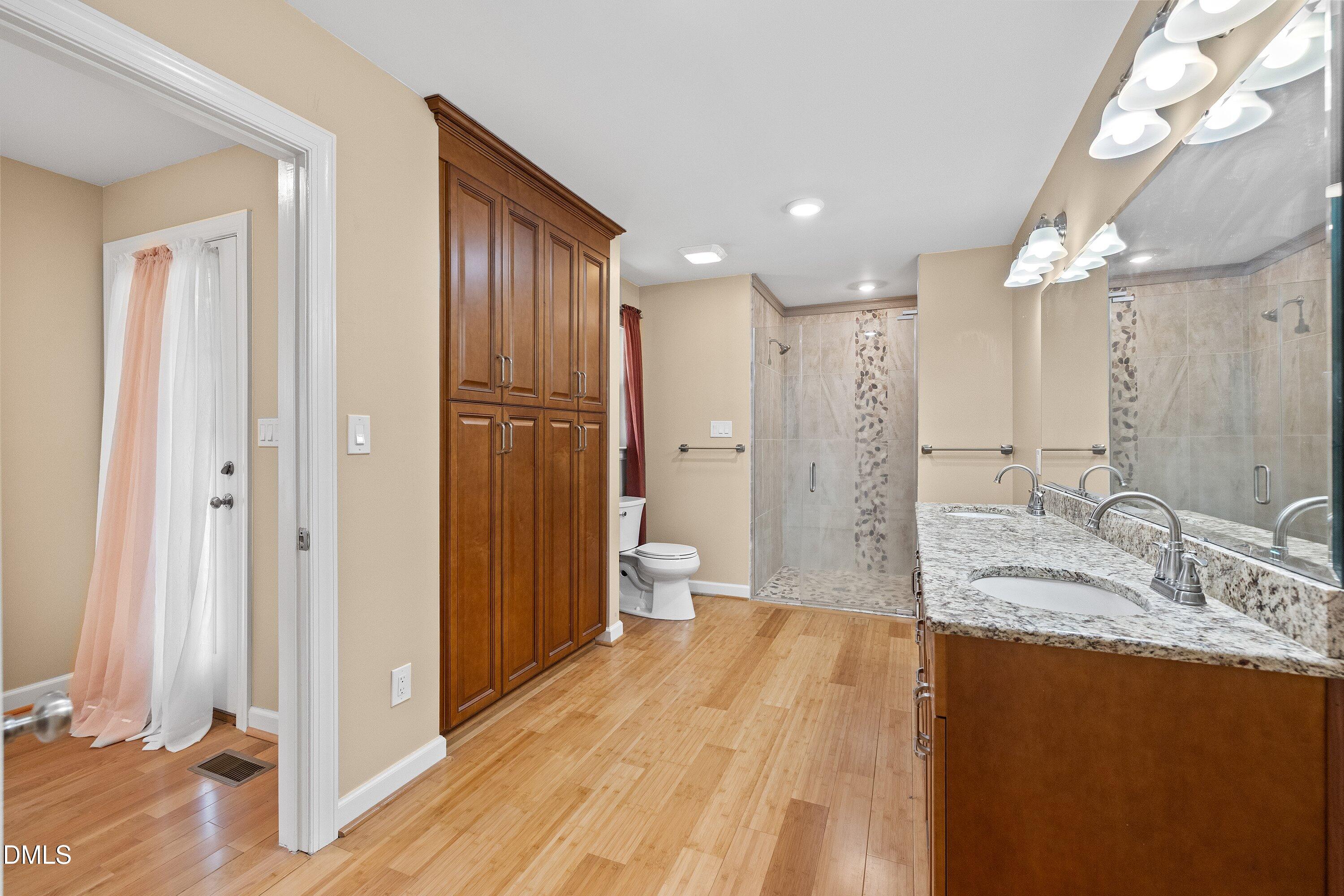 8133 Holly Forest Road Wake Forest, NC 27587 - Photo 27 of 50 a bathroom with a granite countertop sink a toilet a large mirror and shower