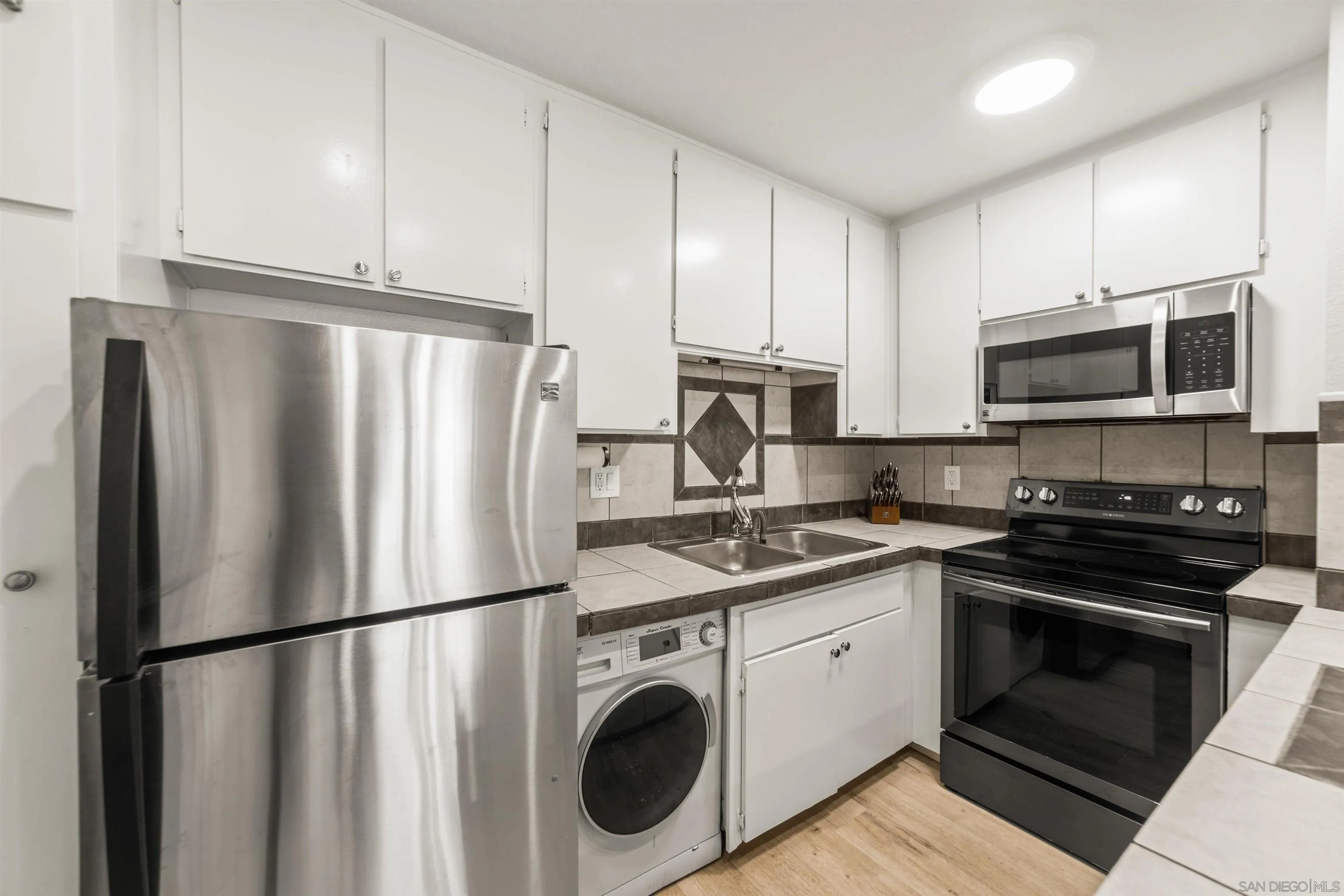 6370 Rancho Mission Road, Unit 913 San Diego, CA 92108 - Photo 7 of 30 a kitchen with stainless steel appliances a refrigerator sink and microwave
