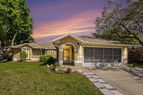 a front view of a house with a yard and potted plants