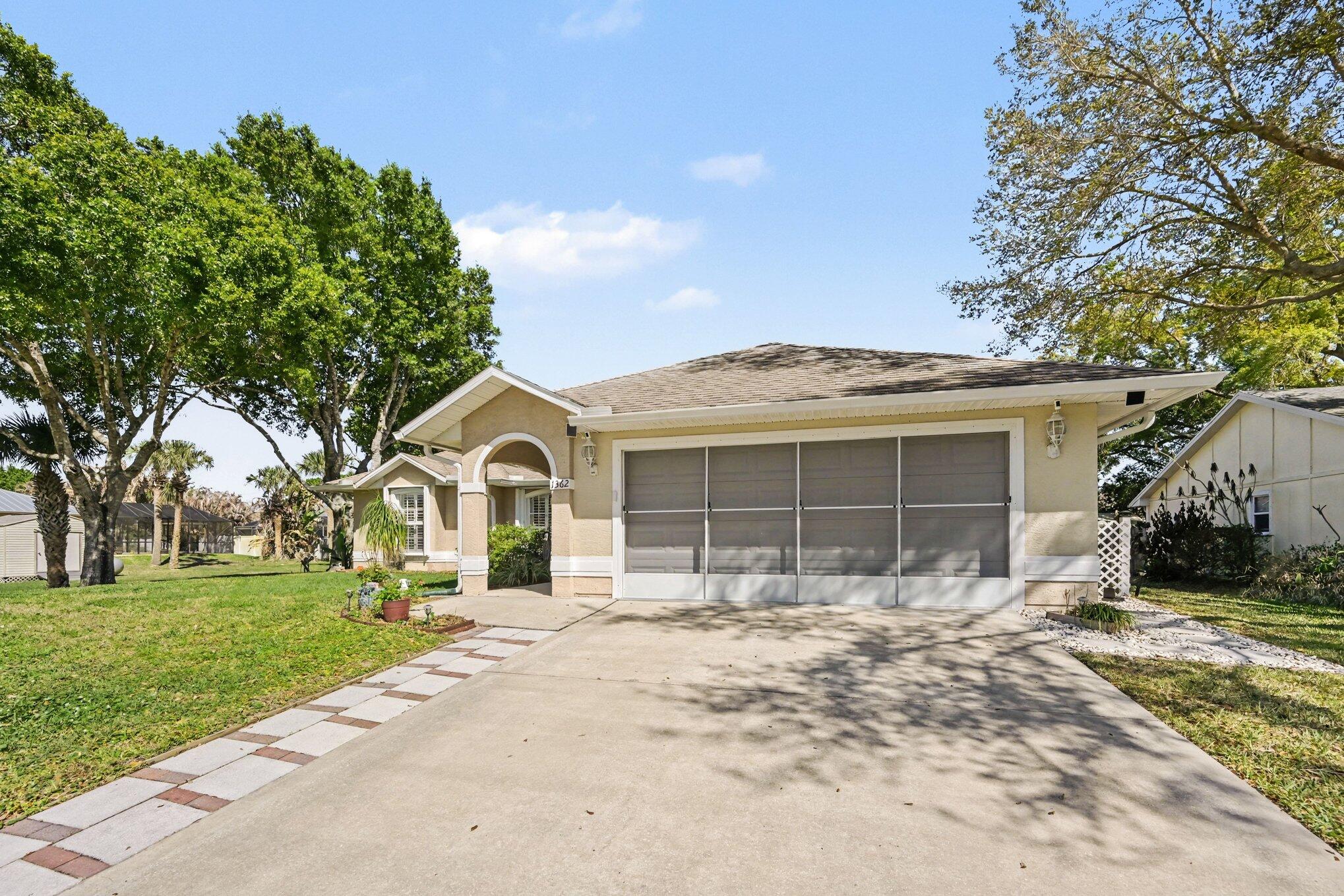 1362 Seahouse Street Sebastian, FL 32958 - Photo 3 of 28 a front view of a house with a yard and garage