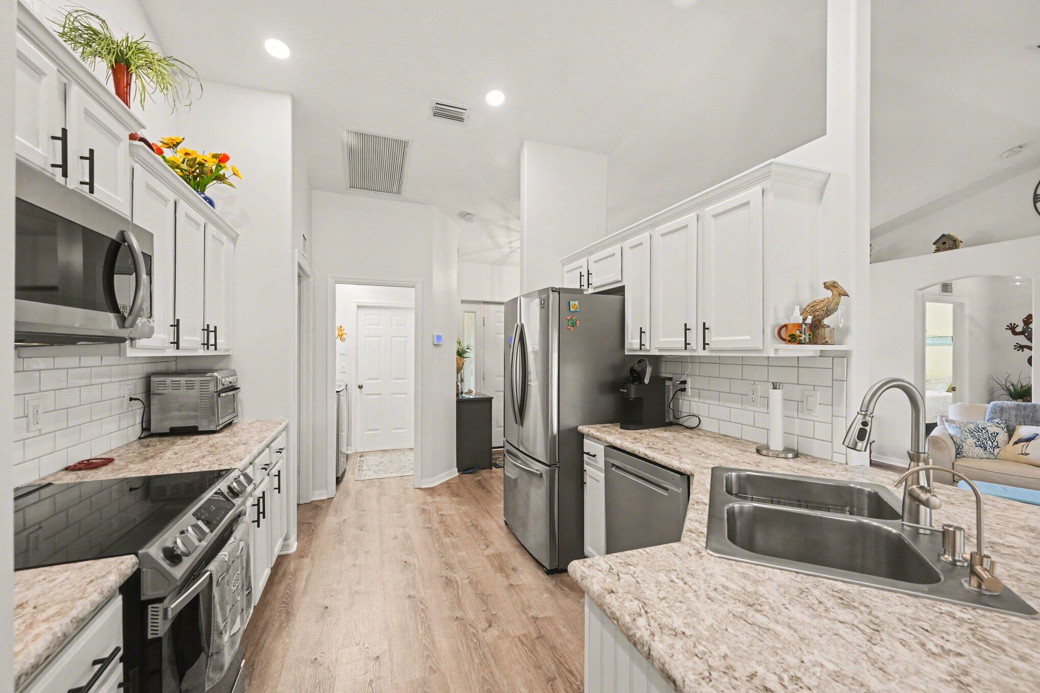 1362 Seahouse Street Sebastian, FL 32958 - Photo 6 of 28 a kitchen with granite countertop a sink stove and refrigerator