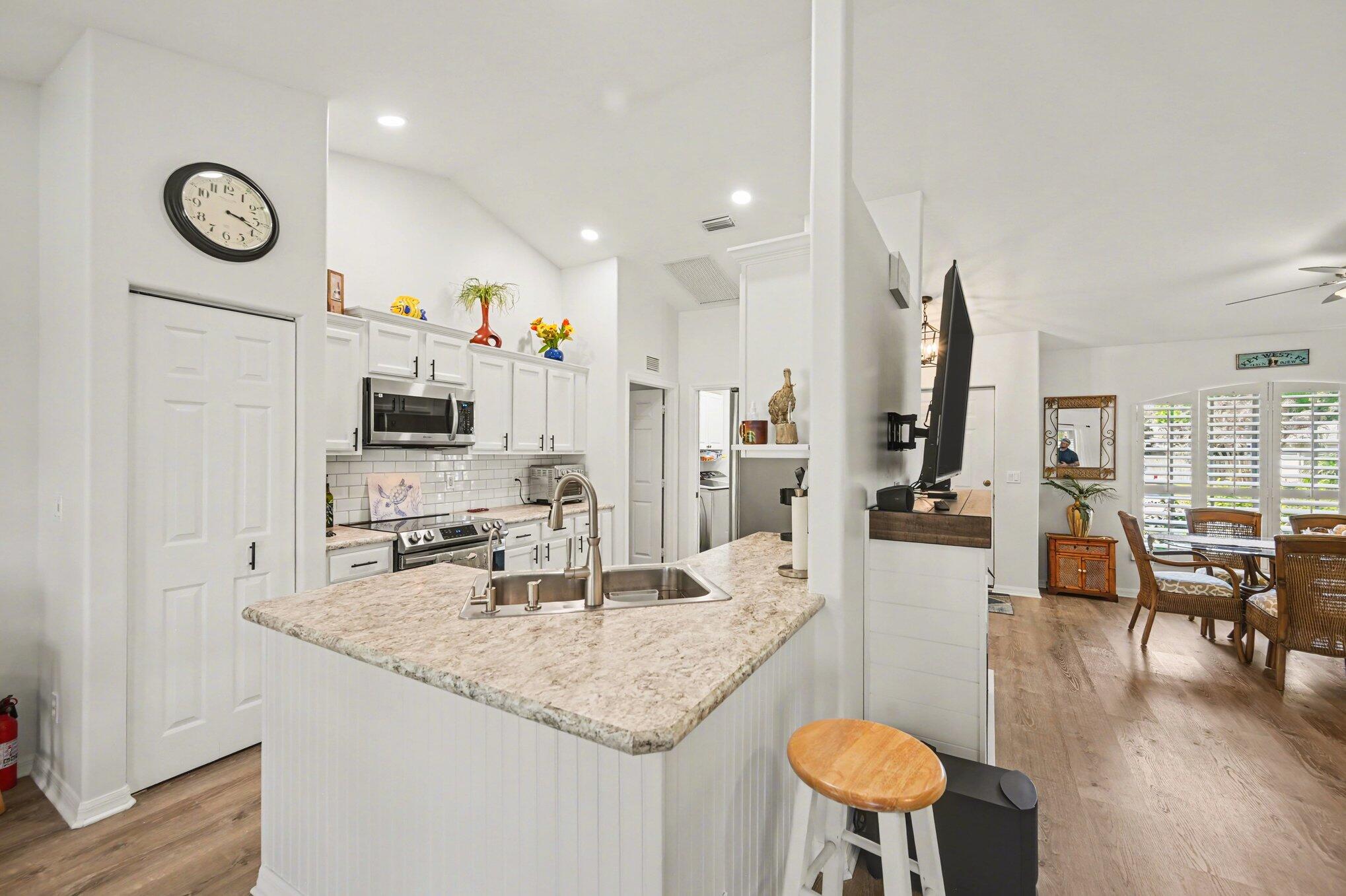 1362 Seahouse Street Sebastian, FL 32958 - Photo 8 of 28 a kitchen with stainless steel appliances granite countertop a kitchen island a stove a table and chairs with wooden floor