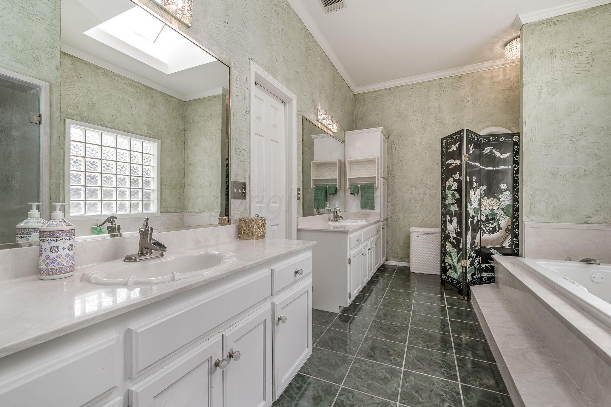 7809 Bent Tree Drive Amarillo, TX 79121 - Photo 16 of 32 a bathroom with a double vanity sink a mirror and a bathtub
