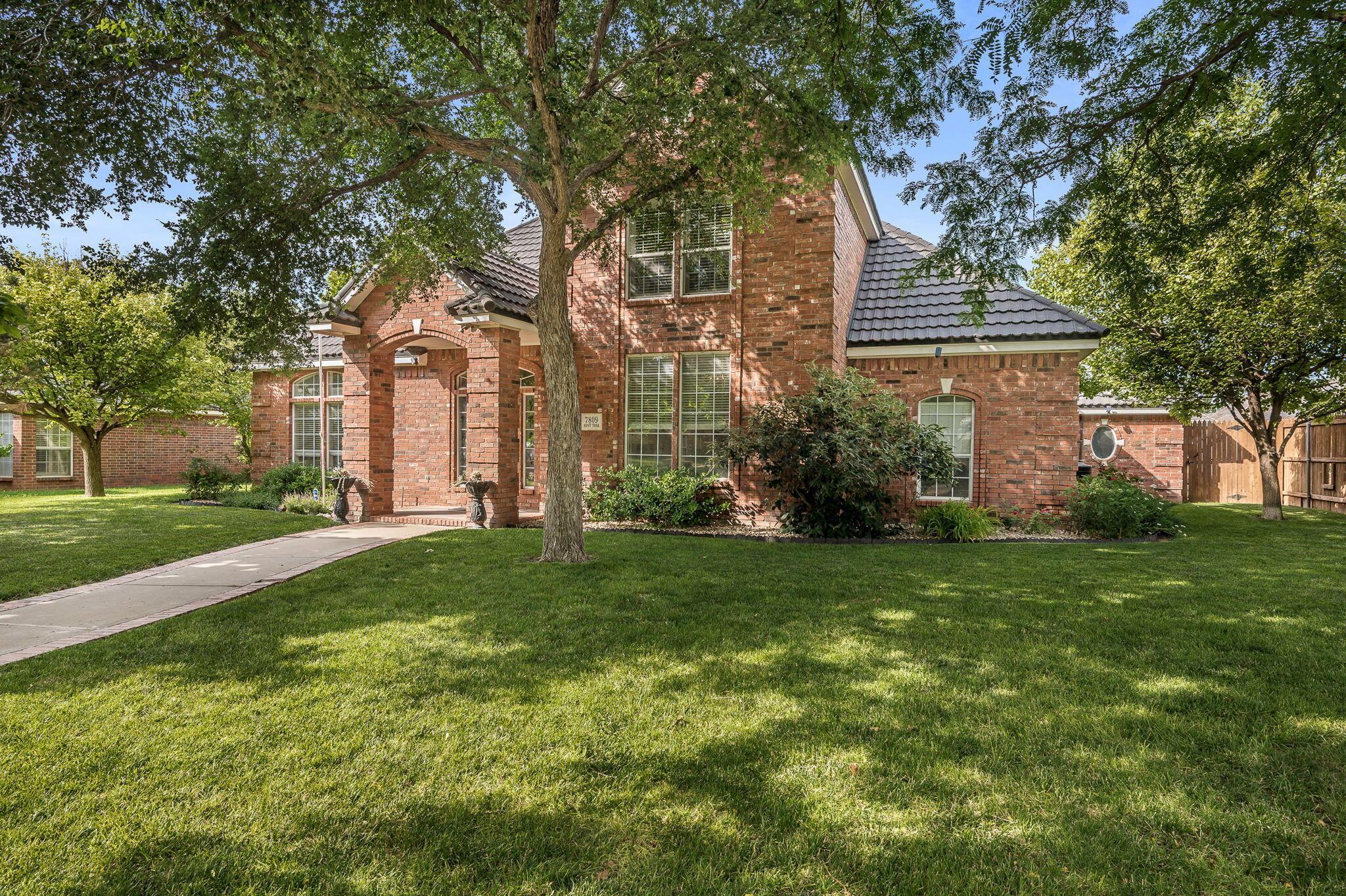 7809 Bent Tree Drive Amarillo, TX 79121 - Photo 2 of 32 a view of a house next to a big yard and large trees