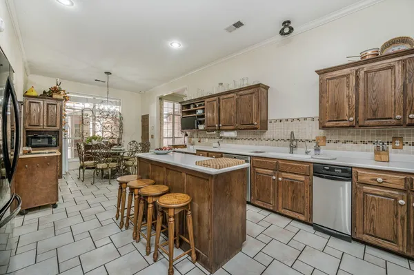 a kitchen with kitchen island granite countertop a sink counter top space appliances and cabinets