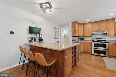 a kitchen with stainless steel appliances granite countertop a stove a sink dishwasher and a refrigerator with wooden floor