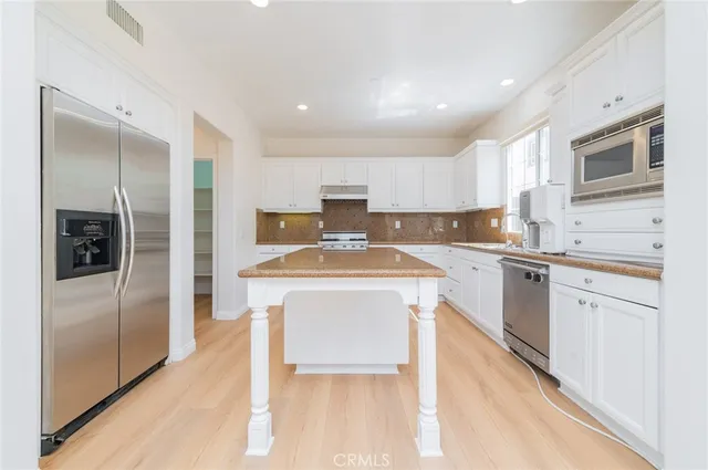 a kitchen with stainless steel appliances granite countertop a refrigerator a stove and a sink with wooden floor