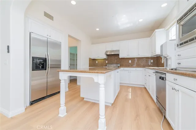 a kitchen with white cabinets and stainless steel appliances