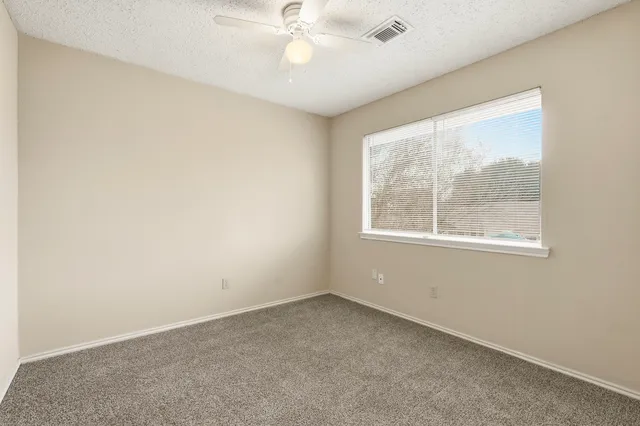 an empty room with a window and a fan