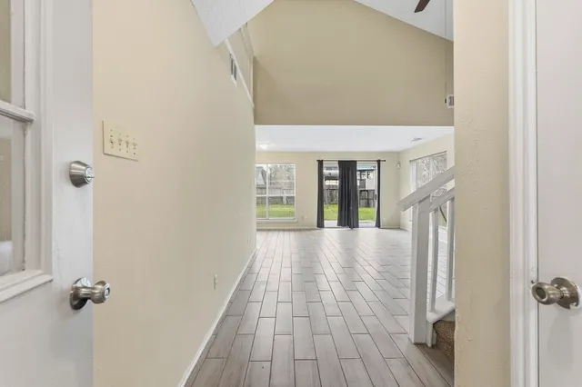 a view of a hallway with wooden floor and a bathroom