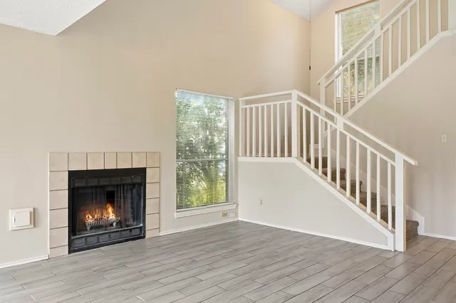 a view of an empty room with wooden floor fireplace and a window