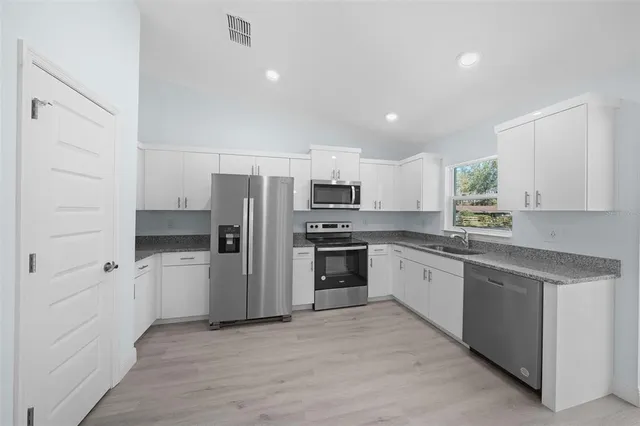 a kitchen with a refrigerator a sink and dishwasher a oven with wooden floor