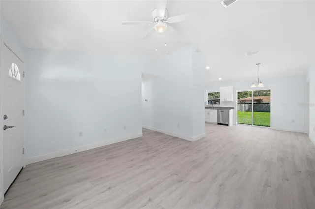 an empty room with wooden floor staircase and windows