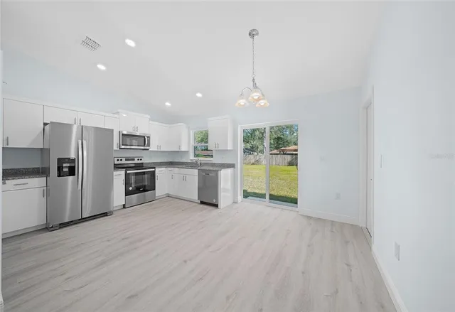 a view of kitchen with stainless steel appliances granite countertop a refrigerator a stove top oven a sink and dishwasher with wooden floor